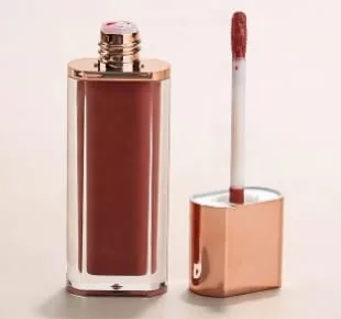 An open LipAfrika lip gloss beside its rose-gold cap and applicator